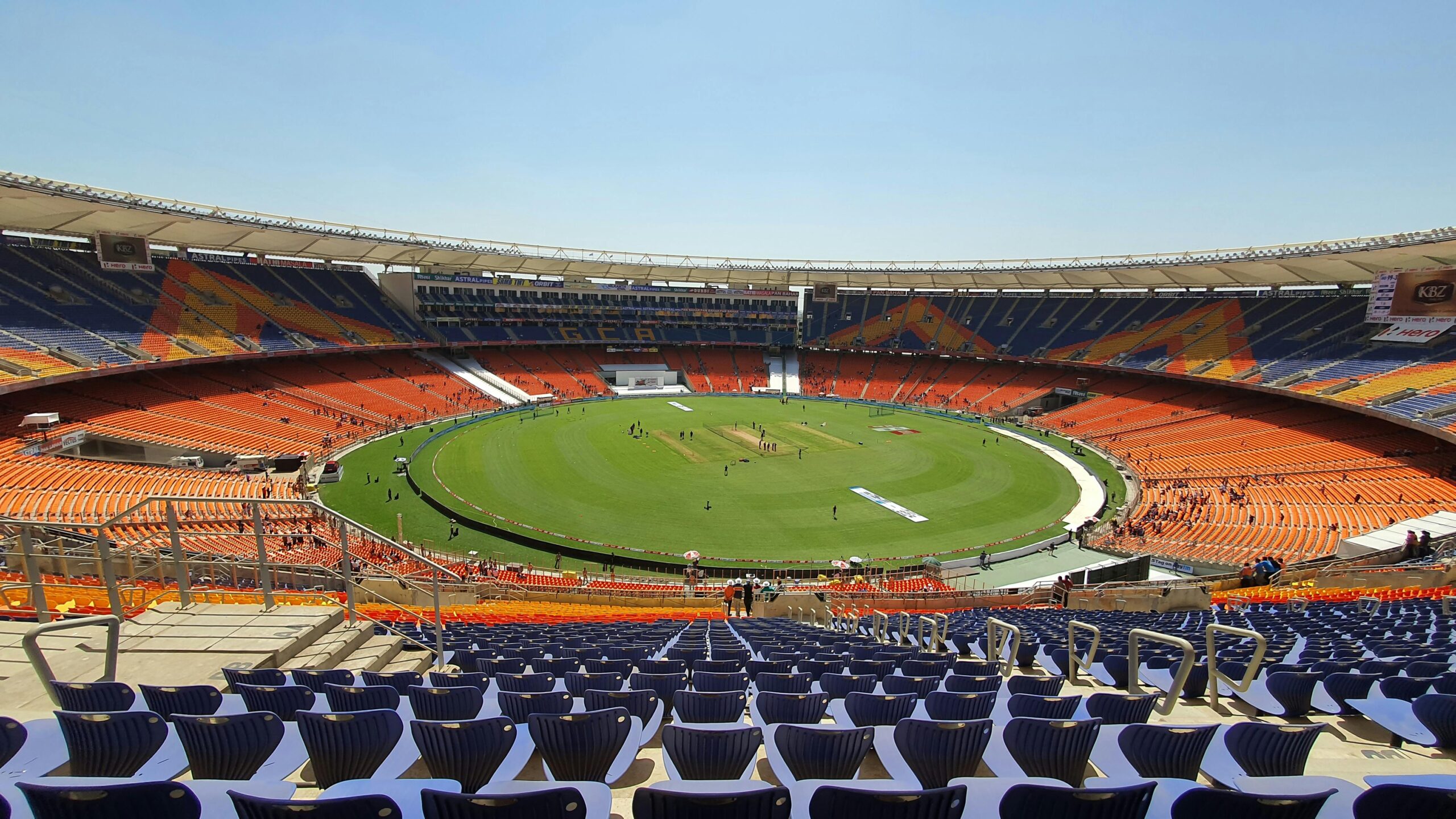 Wide shot of graffiti-adorned Narendra Modi Stadium, highlighting its expansive seating and cricket field.